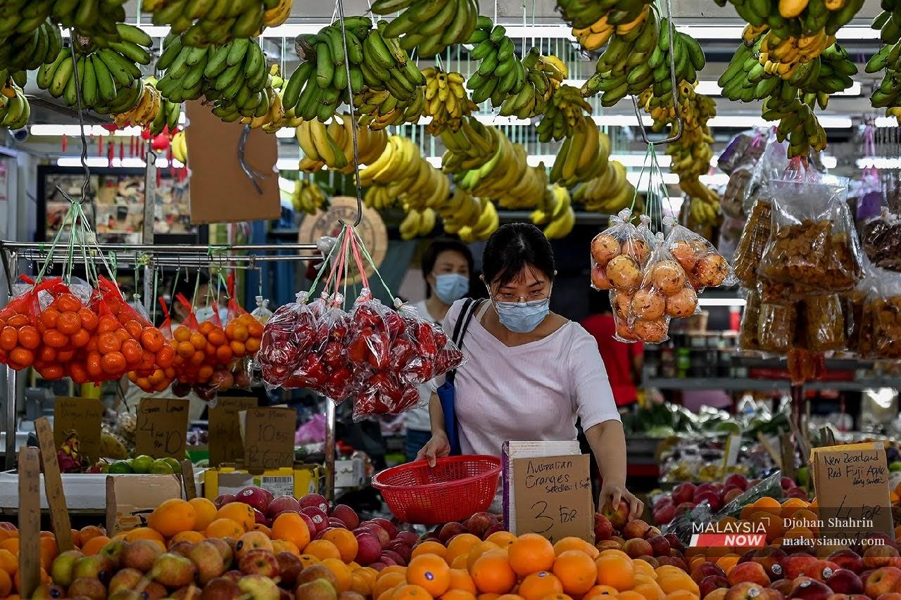 Seorang wanita dilihat mematuhi SOP ketika membeli buah-buahan di sebuah gerai di USJ 10, Subang Jaya.