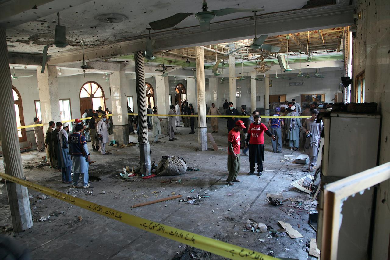 Rescue workers and police officers examine the site of a bomb explosion in a religious school in Peshawar, Pakistan Oct 27. Photo: AP