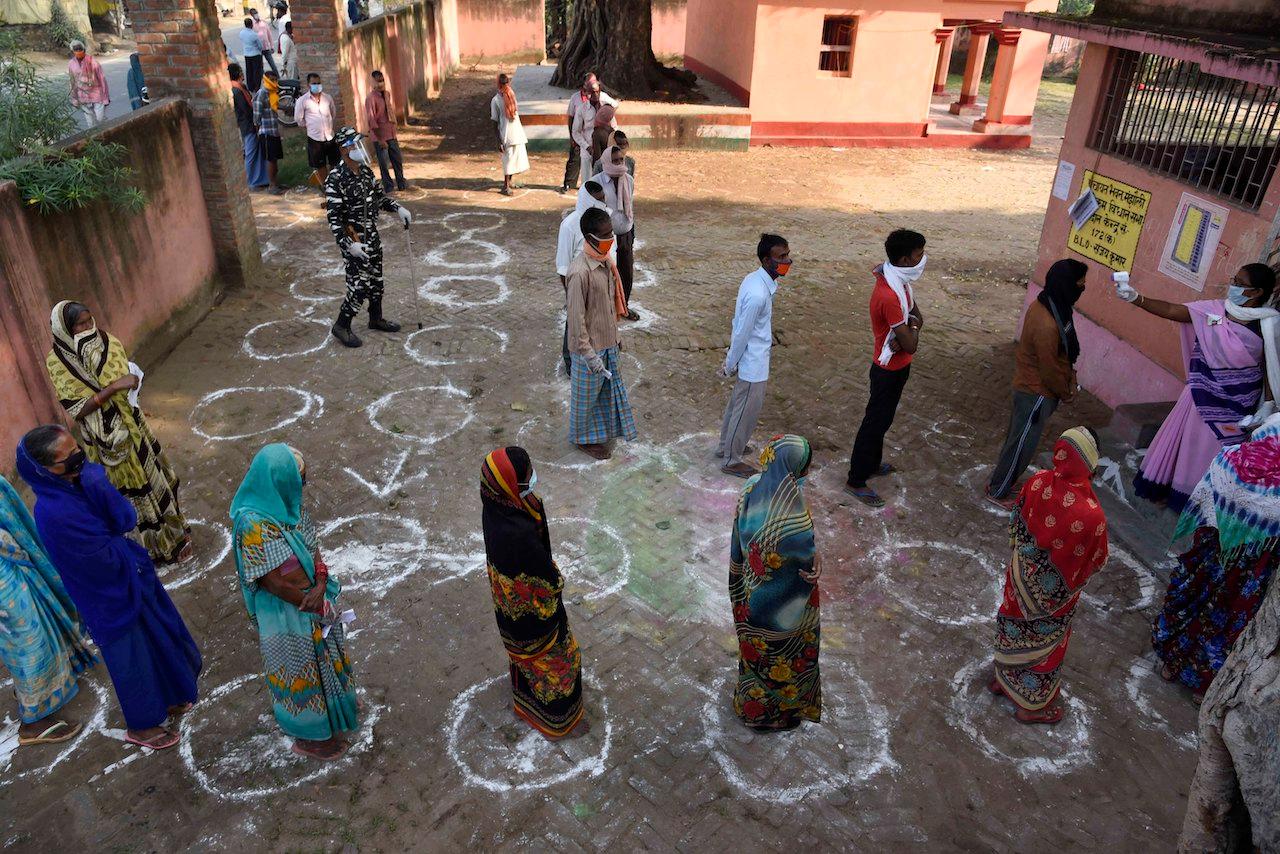 Voters stand in line maintaining social distance at a polling station, during the first phase of state elections at Paliganj, in the eastern state of Bihar on Oct 28. Photo: AP
