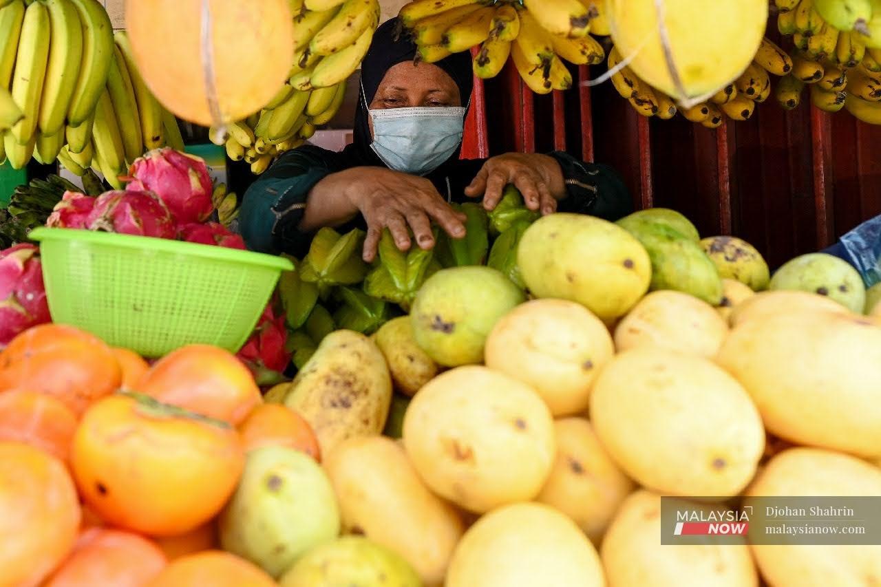 Seorang peniaga buah, Norhayati Dahfar, 55, menyusun buah-buahan di kedai miliknya di Kampung Pandan, Kuala Lumpur.