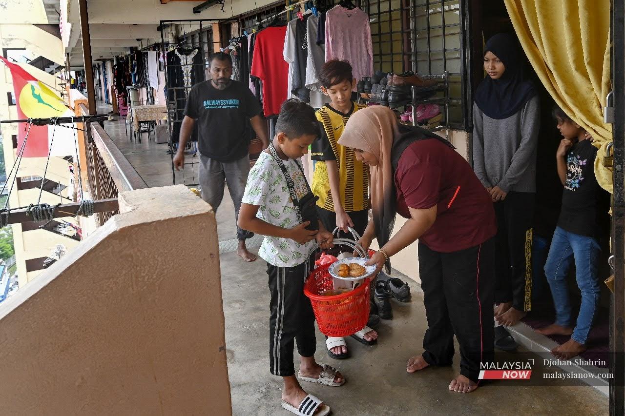Muhammad Farid Nahur Yusof, 12, (kiri) menjual kuih dari pintu ke pintu sepanjang perlaksanaan PKPB bagi membantu ibunya yang merupakan ibu tunggal di flat Sri Perak, Sentul, Kuala Lumpur.