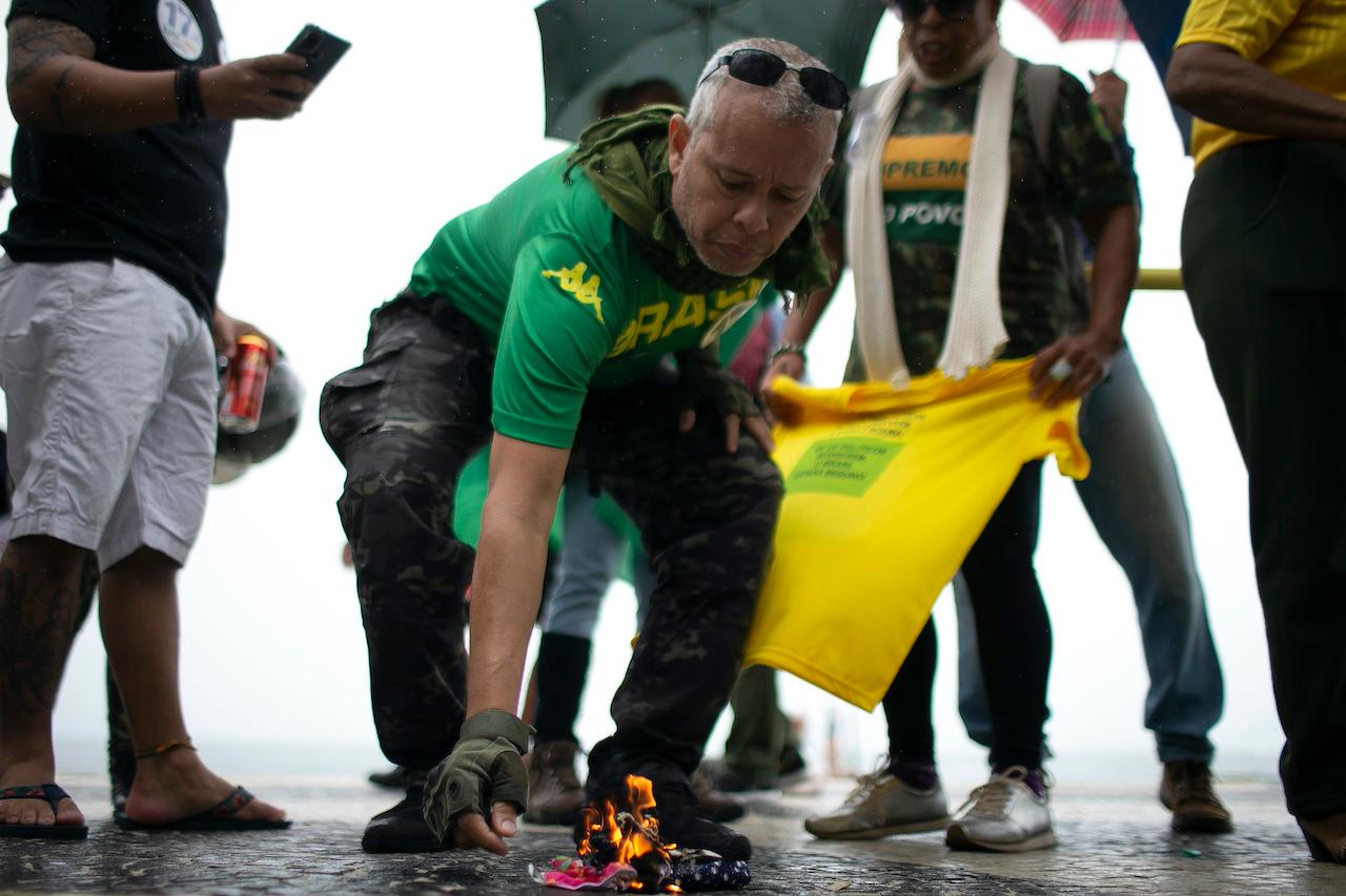 Supporters of Brazilian President Bolsonaro burn protective masks while rallying in favour of his position that no one will be forced to use them and get an eventual coronavirus vaccine, on Copacabana beach in Rio de Janeiro, Brazil, Nov 1. Photo: AP
