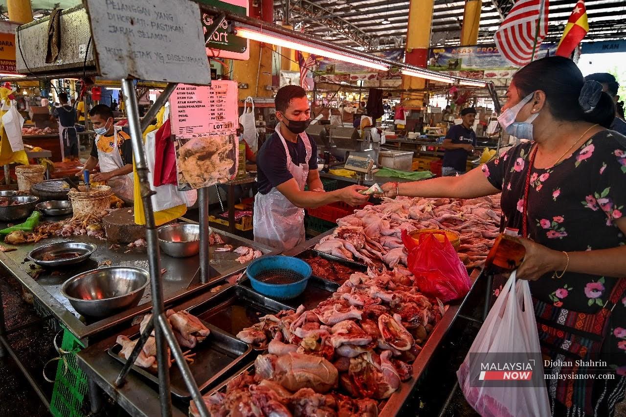 Seorang pelanggan membeli ayam segar di Pasar Borong Selangor, Seri Kembangan, mematuhi SOP kementerian kesihatan dengan memakai pelitup muka.