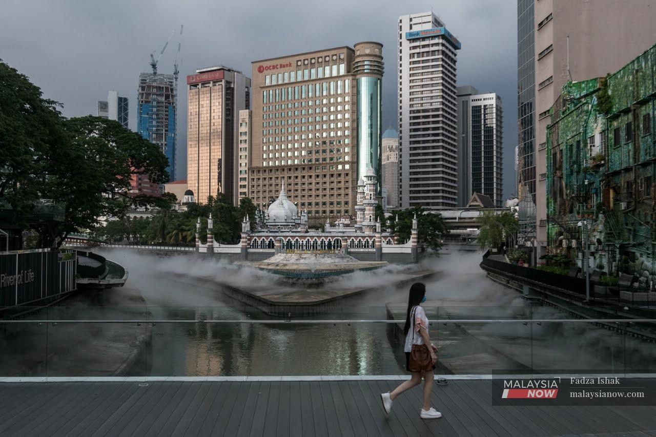 A pedestrian crosses a bridge near Masjid Jamek in Kuala Lumpur, where the Gombak and Klang rivers meet.