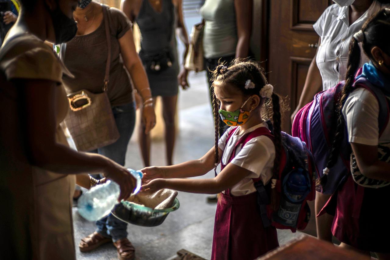 Wearing a mask as a precaution amid the spread of the coronavirus, a student washes her hands upon arrival to school in Havana, Cuba, Nov 2. Photo: AP