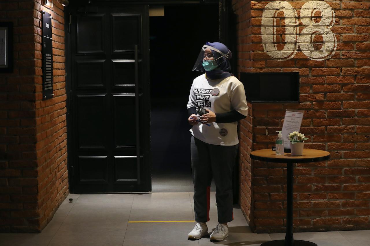 An attendant wearing a protective face shield waits for customers at a cinema in Jakarta, Oct 23. Photo: AP