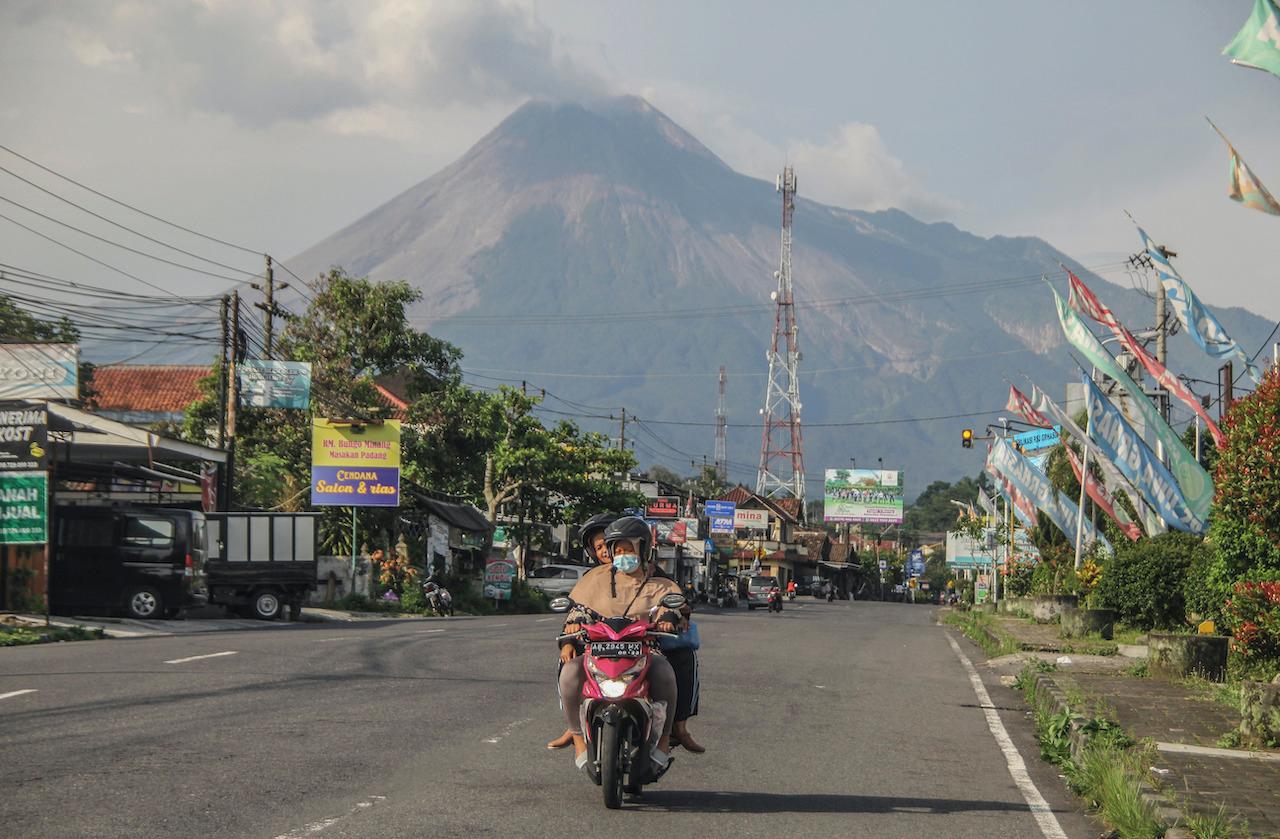 A motorist rides past by as Mount Merapi looms in the background, in Sleman, Indonesia, Nov 6. Photo: AP