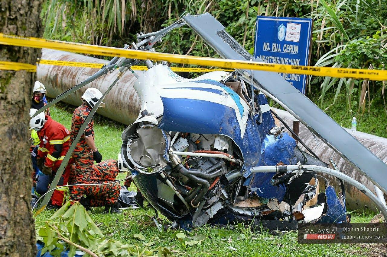 Personnel from the Fire and Rescue Department gather at the wreckage of a helicopter which crashed in a field at Taman Melawati in Selangor at noon today.