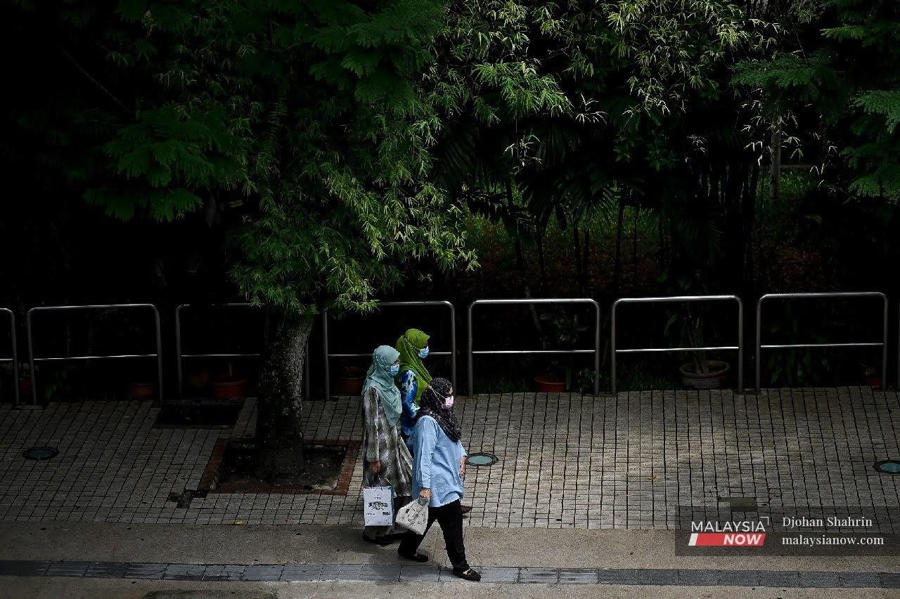 Tiga wanita berjalan kaki dengan memakai pelitup mulut di Jalan Raja Laut, Kuala Lumpur.