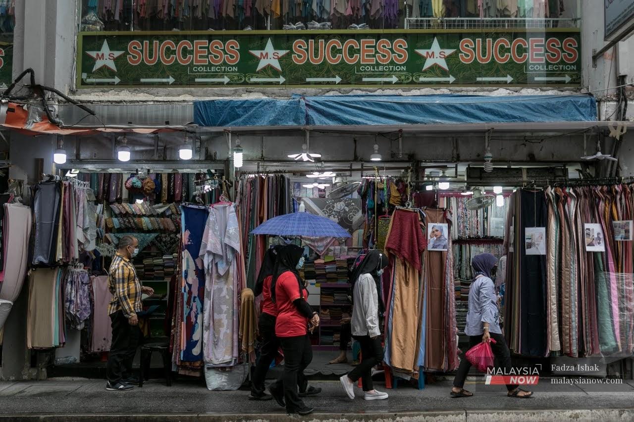 A group of worker walking infront of a textile shop in Kuala Lumpur.