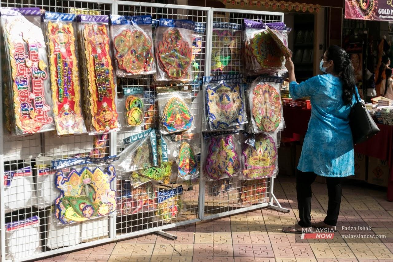 Seorang wanita memakai pelitup muka dilihat memilih dekorasi Deepavali di sebuah kedai di Brickfields, Kuala Lumpur.