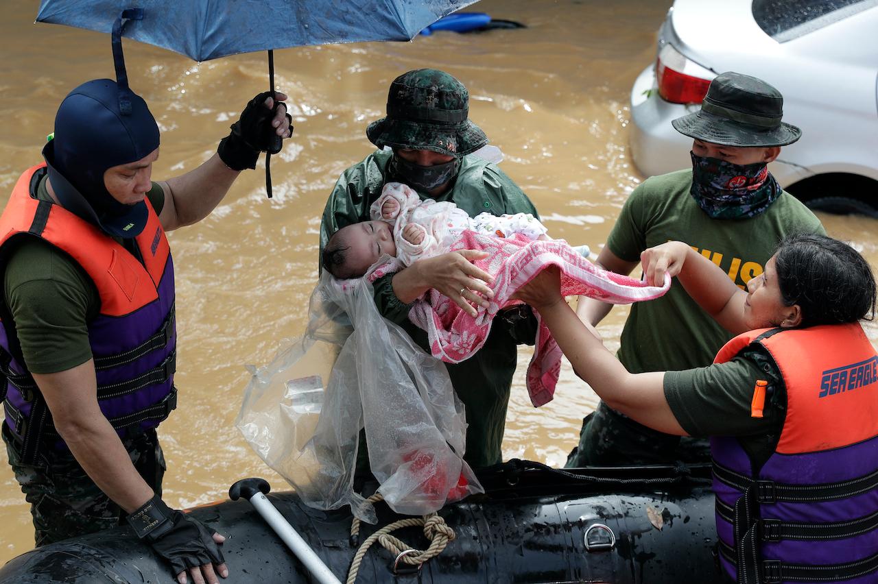 Rescuers carry a baby as floods continue to rise in Marikina, Philippines due to typhoon Vamco on Nov 12. Photo: AP