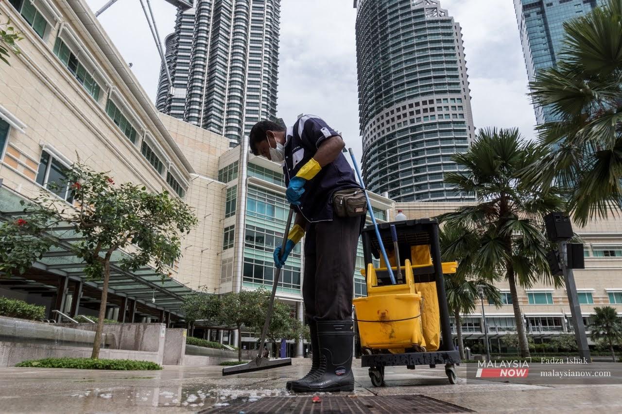 Seorang pekerja pembersihan mengenakan pelitup muka ketika melakukan tugas di Taman KLCC, Kuala Lumpur.
