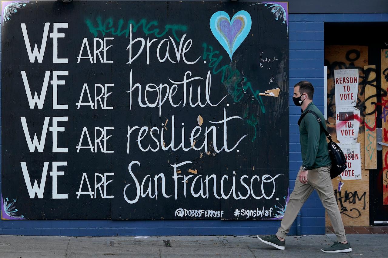 A man in a face mask walks past a sign during the coronavirus outbreak in San Francisco, Nov 12. Based on latest reports, the countries with the most new deaths were the US, followed by Italy and the UK. Photo: AP