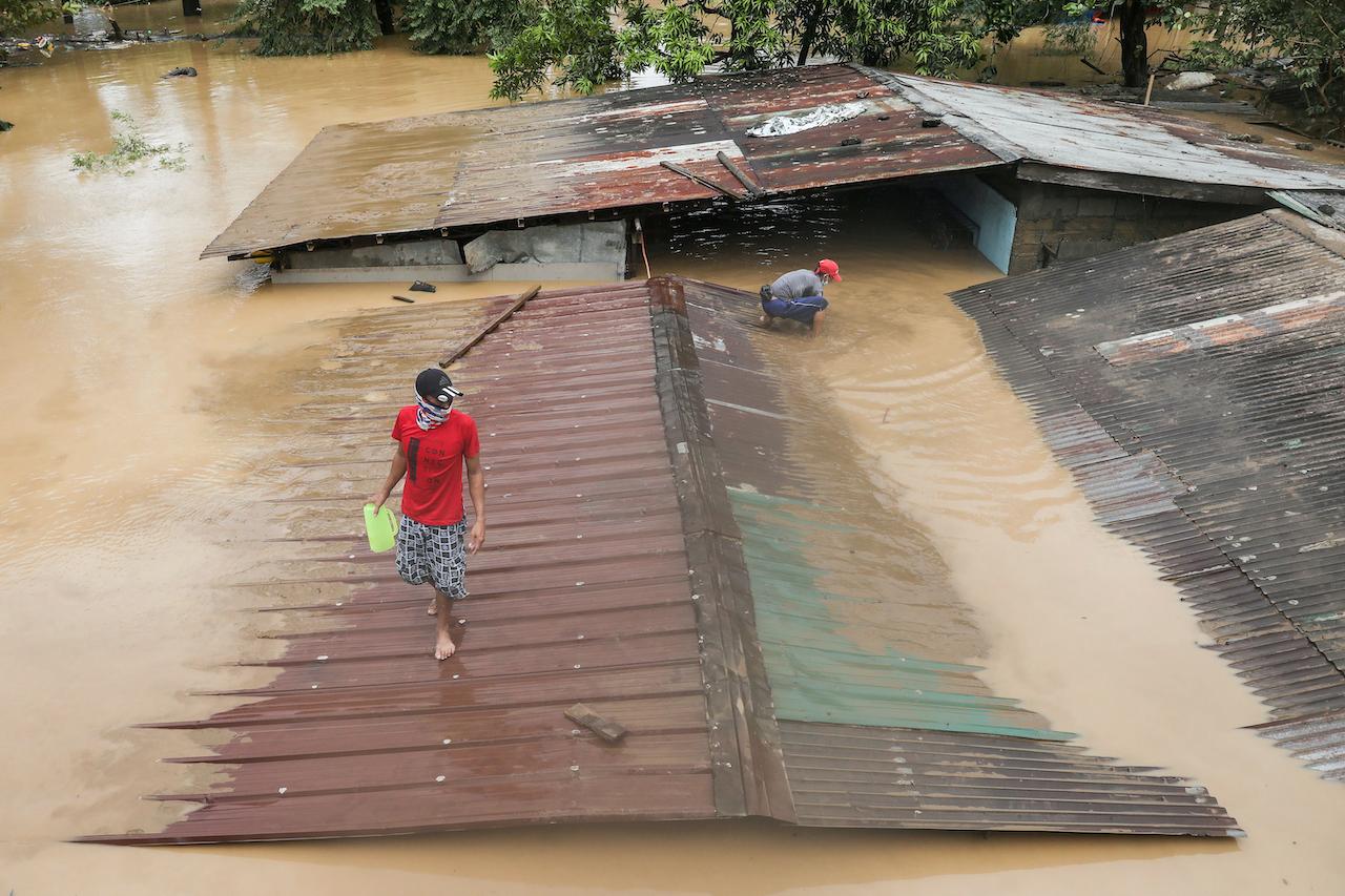 A man walks on the roof of a submerged house as floods inundate villages due to typhoon Vamco in Rizal province, Philippines on Nov 12. Photo: AP