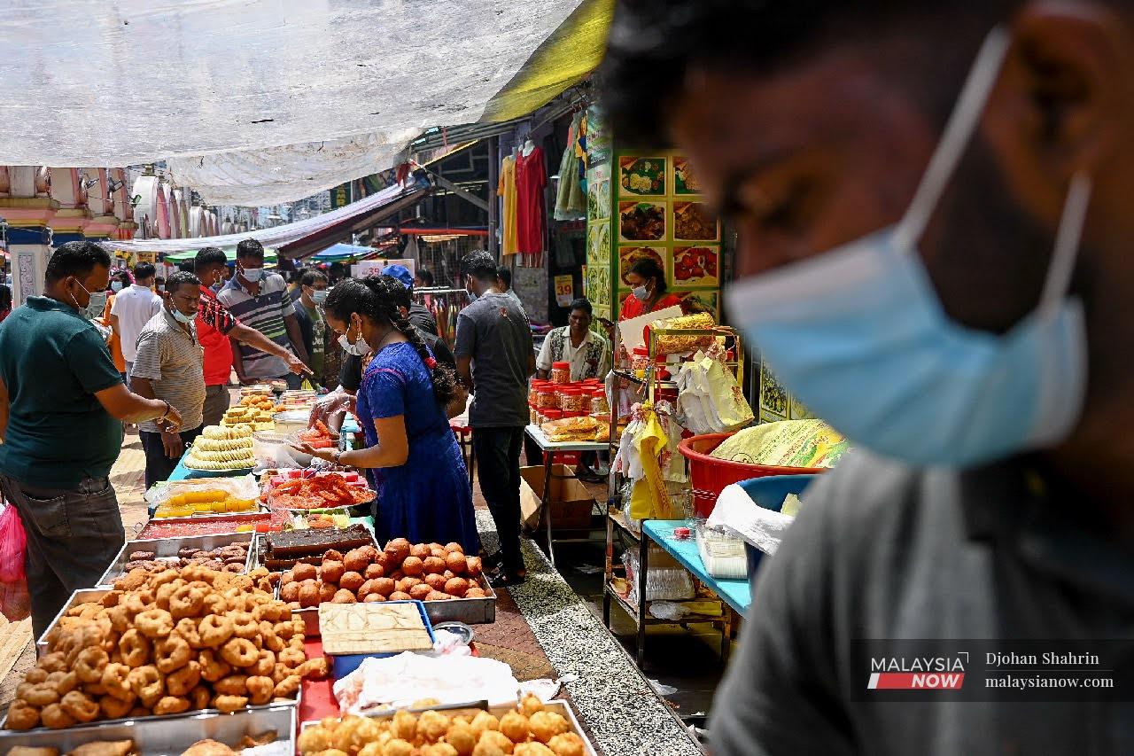 Shoppers wearing face masks to ward off the spread of Covid-19 buy kuih and snacks from vendors in Brickfields, Kuala Lumpur ahead of Deepavali celebrations tomorrow.