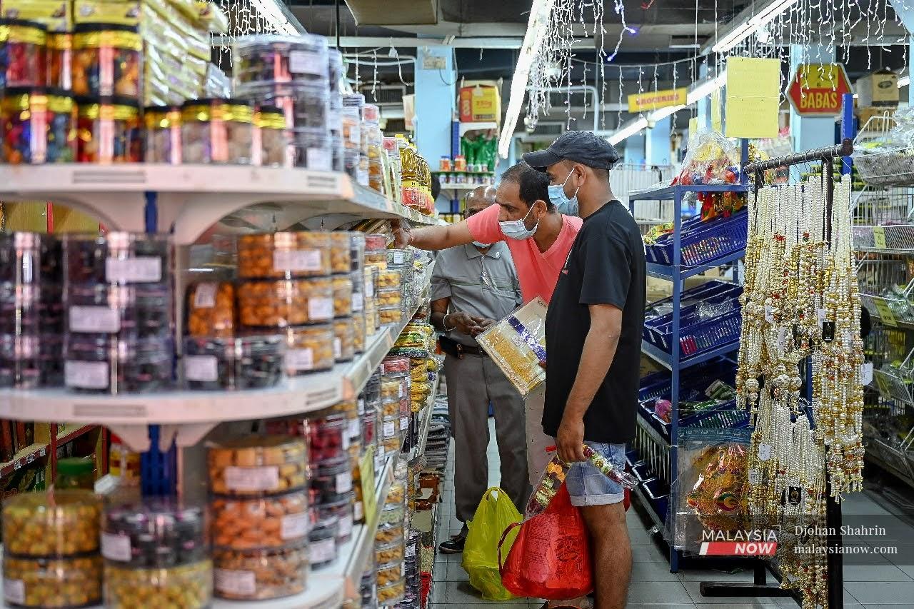 Dua lelaki memakai pelitup muka sedang sibuk membeli barang keperluan sempena sambutan Deepavali esok, di Brickfield, Kuala Lumpur.
