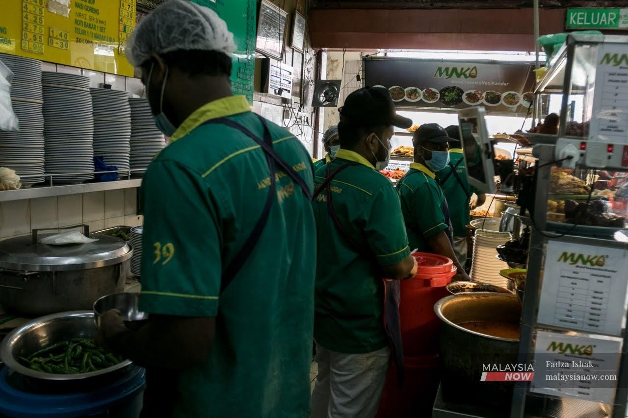 Beberapa pekerja sebuah restoran makanan di Chow Kit, Kuala Lumpur mematuhi SOP dengan memakai pelitup muka semasa bekerja.