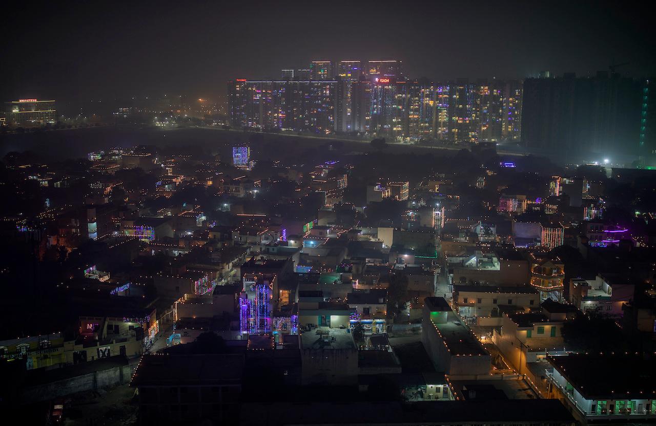 A layer of smog envelops the skyline as residential buildings stand decorated with colourful lights during Deepavali, on the outskirts of New Delhi, India, Nov 14. Photo: AP