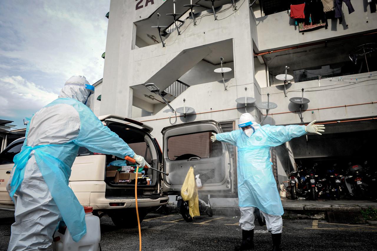 A health worker is hosed down after disinfecting the housing area of a resident believed to have contracted Covid-19 at Taman Desa Genting in Balik Pulau. Photo: Bernama