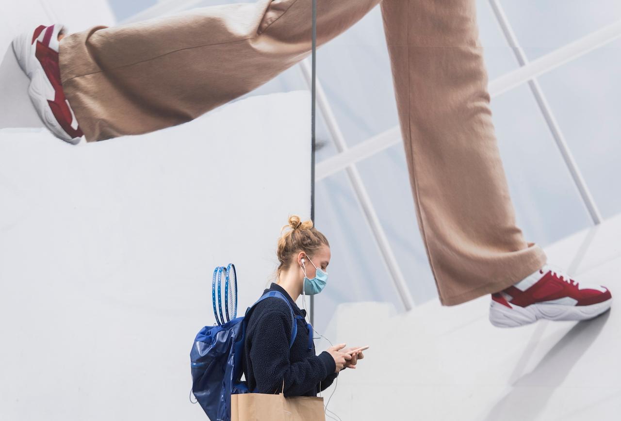 A woman wears a face mask as she walks by a storefront window in Montreal, Nov 14. Photo: AP