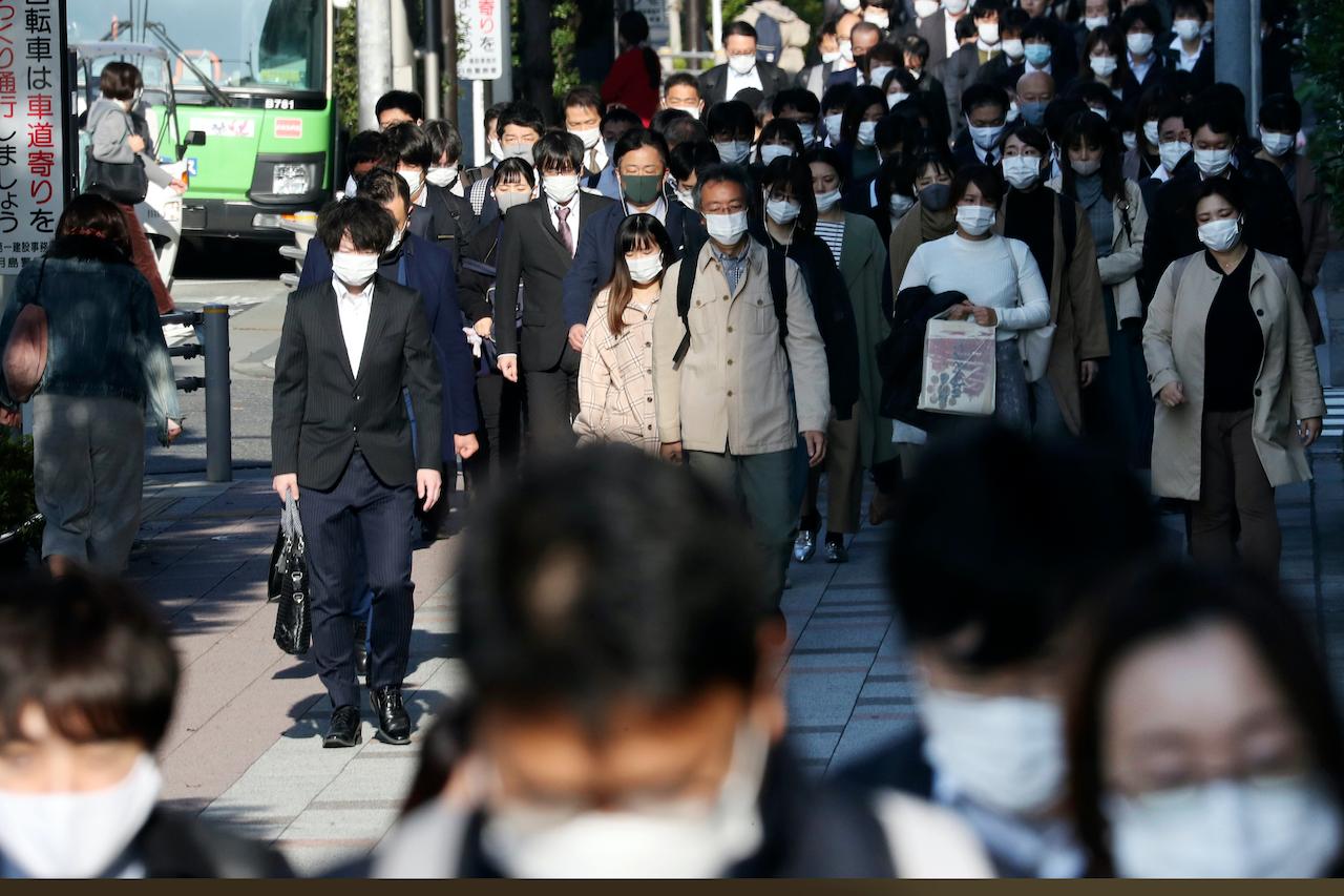 Commuters wearing face masks to protect against the spread of the coronavirus walk on a street in Tokyo, Nov 17. Photo: AP