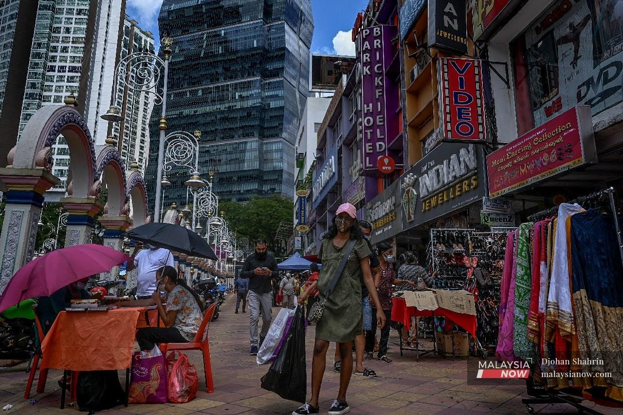 Kelihatan orang ramai melalui kawasan deretan kedai di Brickfield, Kuala Lumpur, mematuhi SOP ketika berada di tempat awam.