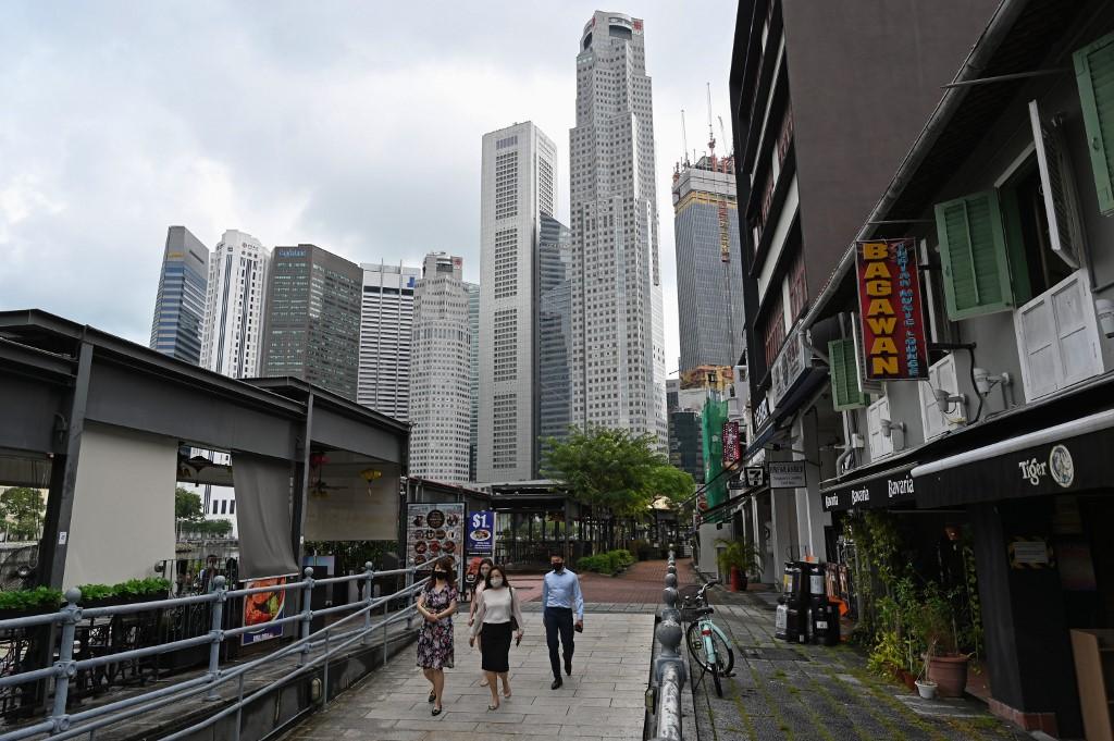 Office workers walk around the financial business district in Singapore on Nov 23. Malaysian workers stranded in the city-state are proving to be a lifeline for hostels struggling to stay afloat. Photo: AFP