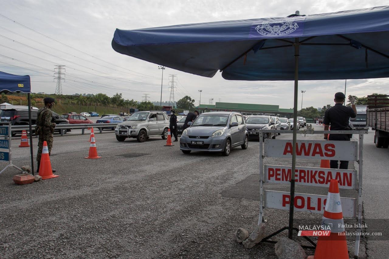 Police officers check vehicles at a road block at Setia Alam in Shah Alam.