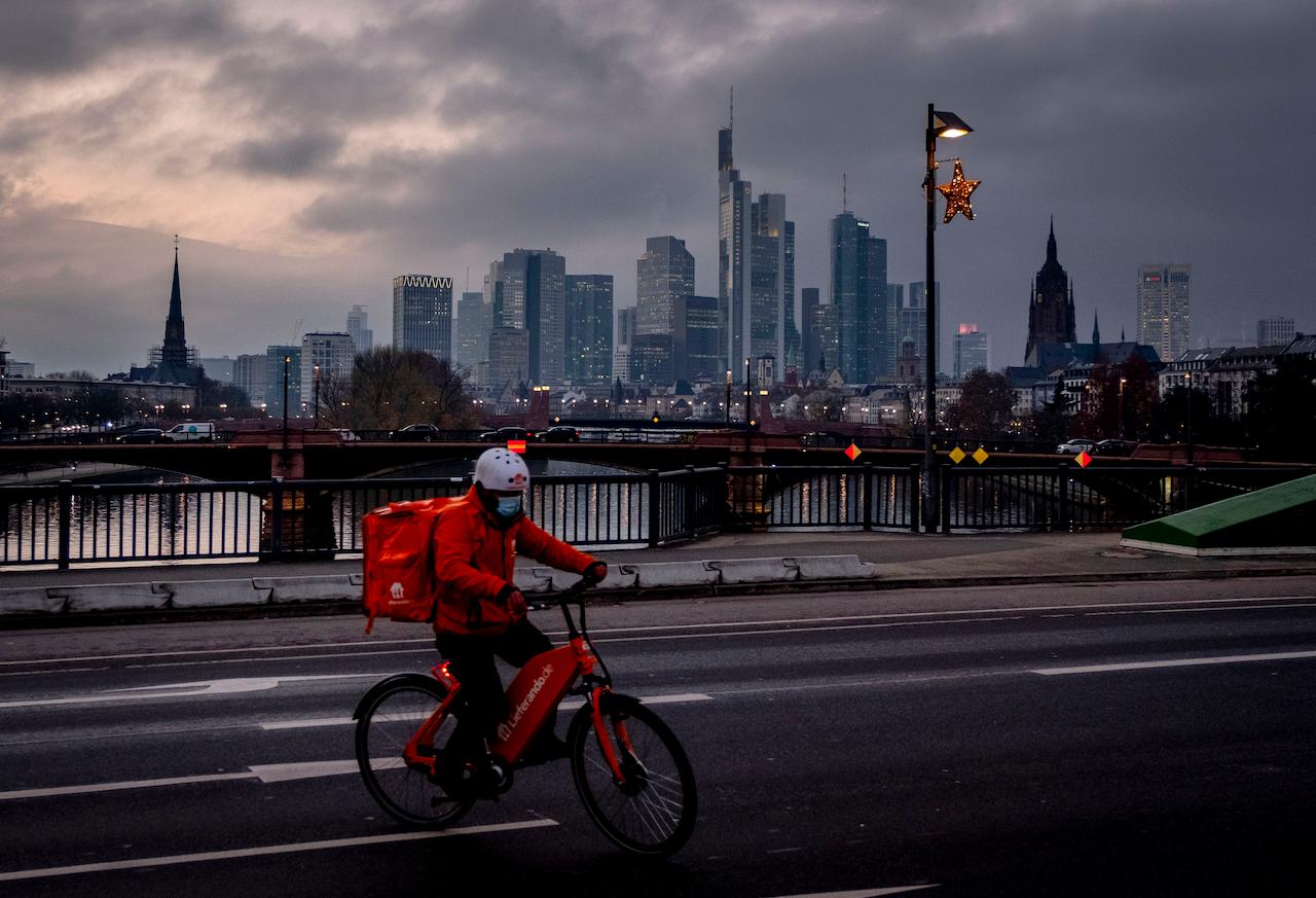 A man wearing a face mask delivers food in downtown Frankfurt, Germany, Nov 26. Photo: AP