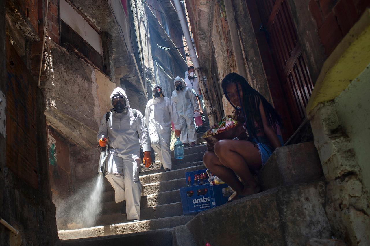 Volunteers spray disinfectant in an alley to help contain the spread of Covid-19, at the Santa Marta slum in Rio de Janeiro, Brazil, Nov 28. Photo: AP