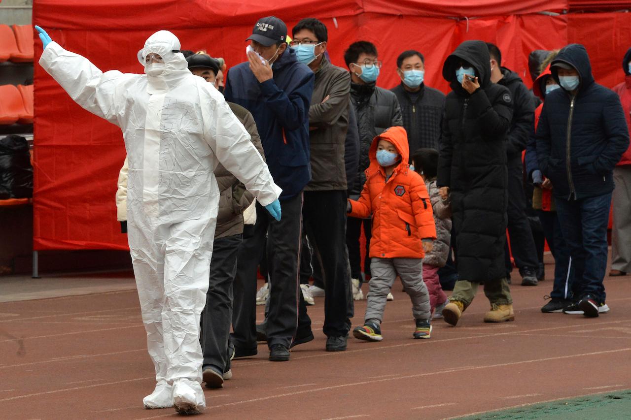 A worker wearing a protective suit gestures to a line of people at a Covid-19 testing site in Tianjin, China, Nov 21. Photo: AP
