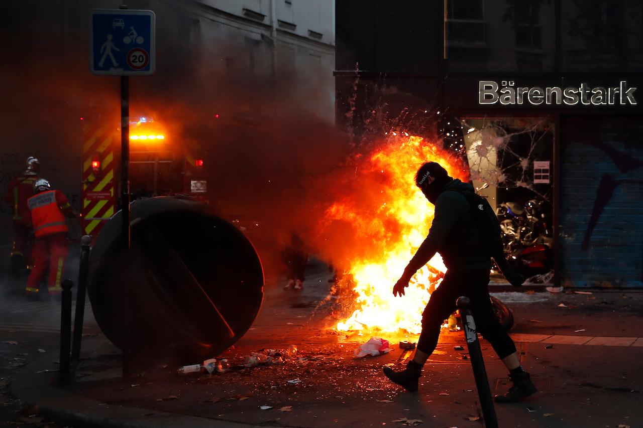 A protester walks past a fire set up by protesters during a demonstration against a security law that would restrict sharing images of police, Nov 28 in Paris. Photo: AP