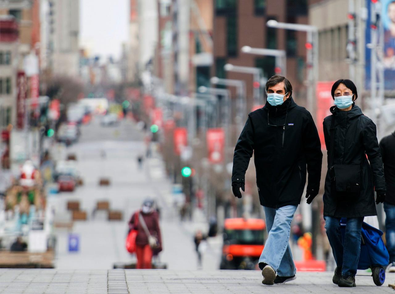 People wear face masks as they walk along a street in Montreal, Nov 22. Photo: AP
