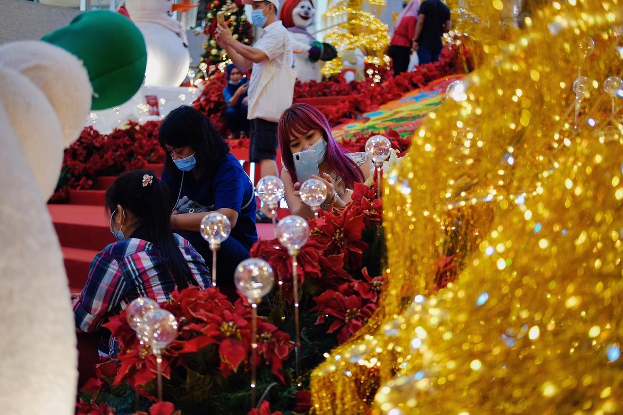 Shoppers wearing face masks take pictures of Christmas decorations at a mall in Kuala Lumpur. Photo: Bernama
