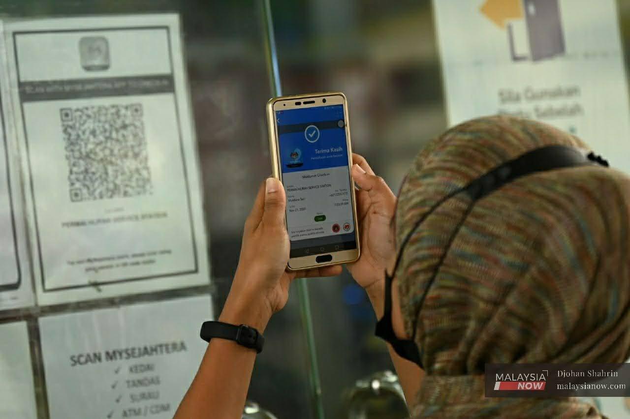 Seorang pengguna MySejahtera menggunakan aplikasi tersebut ketika memasuki ke sebuah premis perniagaan di Taman Tasik Ampang, Kuala Lumpur.