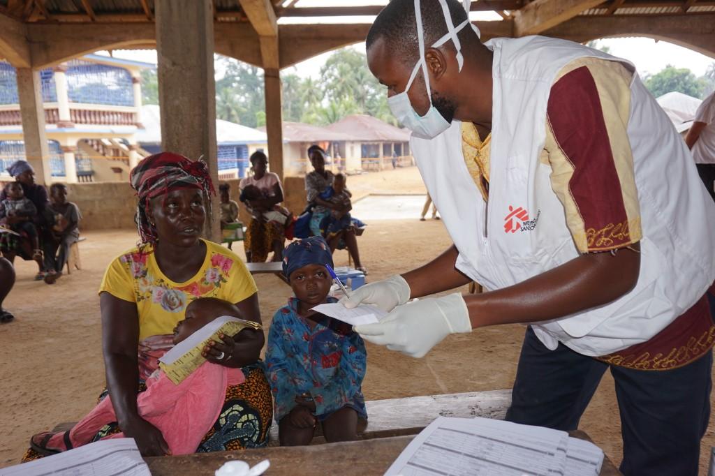 A Doctors Without Borders health worker tends to a mother and her child at a mobile clinic outreach in Manokortuhun village, Kenema district, July 10. Photo: AFP