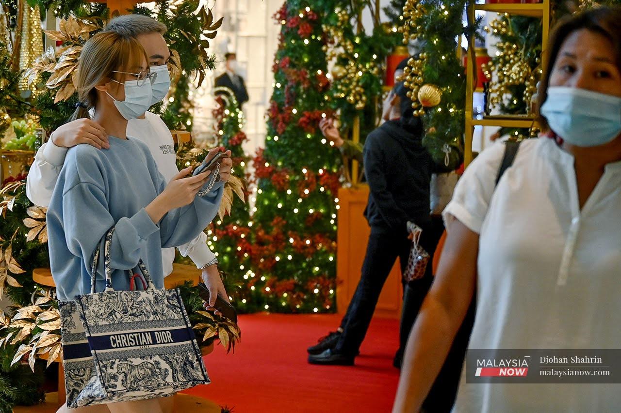 Beberapa pengunjung memakai pelitup mulut dan hidung ketika melalui kawasan dekorasi Krismas semasa berkunjung di pusat membeli belah Pavillion, Bukit Bintang.