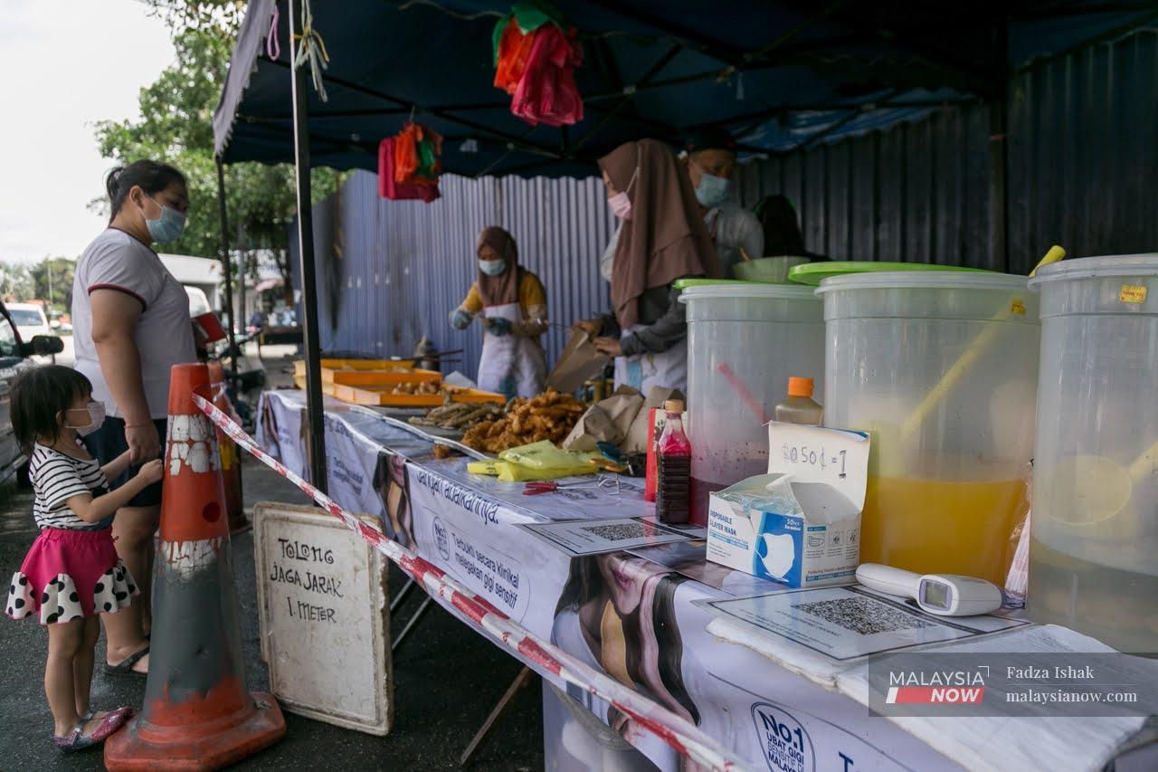A woman and her child stop by a roadside stall selling pisang goreng in Klang.