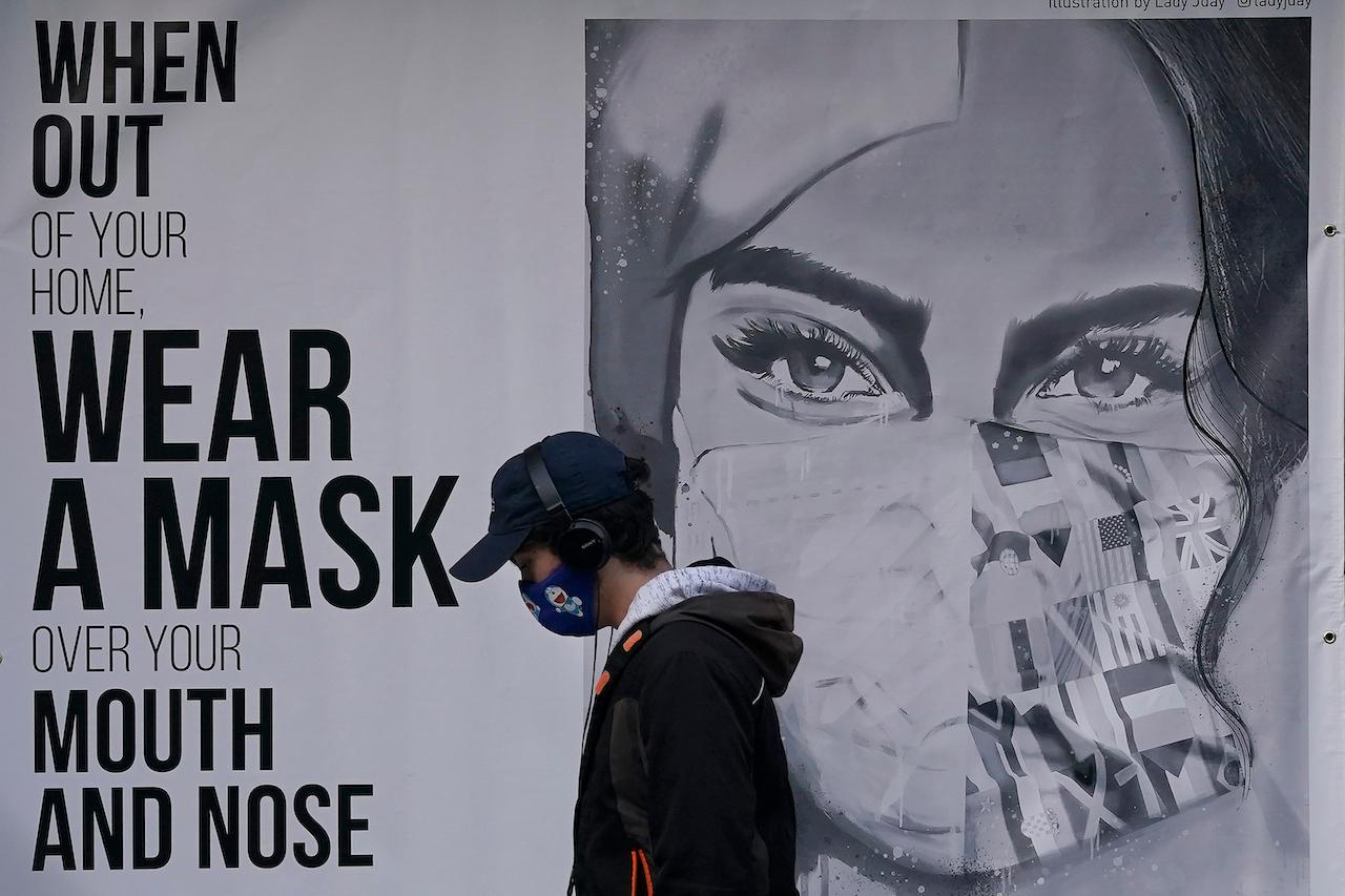 A youth walks past a mural reminding people to wear face masks in San Francisco, California. Photo: AP