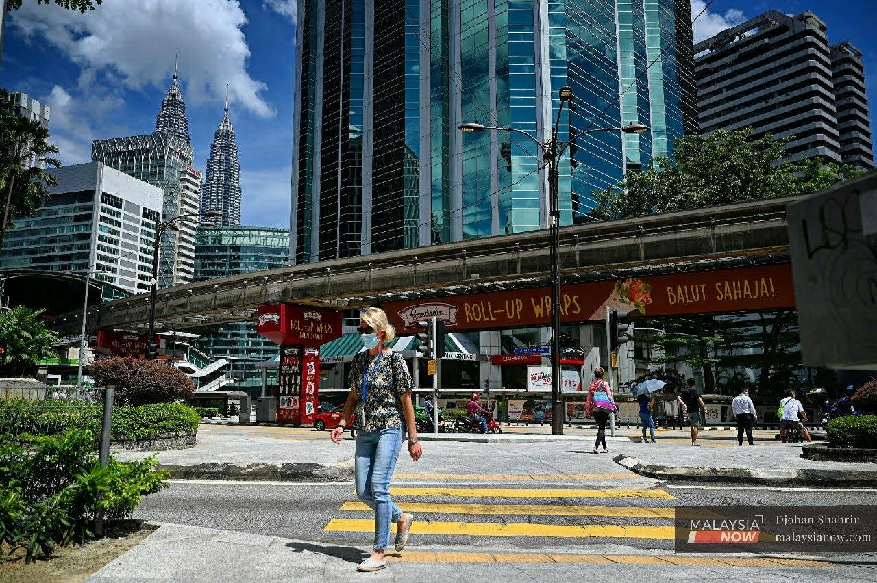 A woman wearing a face mask walks along Jalan Raja Chulan in Kuala Lumpur.