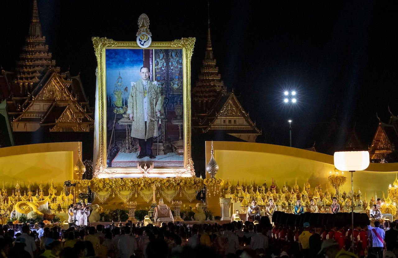 Thai King Maha Vajiralongkorn and members of the royal family sit in front of a giant portrait of late King Bhumibol Adulyadej during a ceremony to mark the anniversary of the birth of the late king at Sanam Luang ceremonial ground in Bangkok, Thailand, Dec 5. Photo: AP