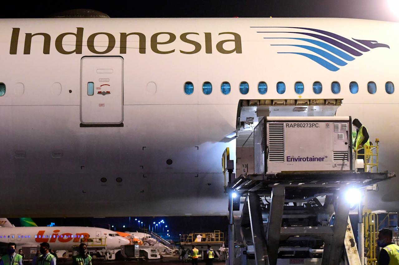 Workers unload a container containing experimental coronavirus vaccines made by Chinese company Sinovac from the cargo bay of a Garuda Indonesia plane at the Soekarno-Hatta International Airport in Tangerang, Indonesia, Dec 6. Photo: AP