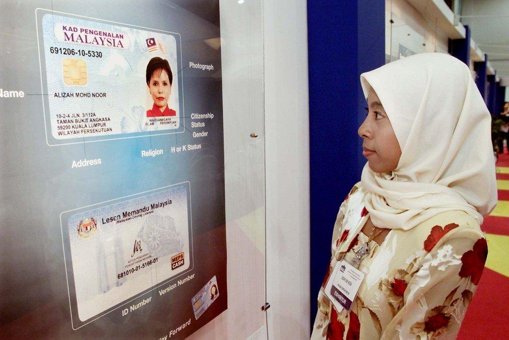 A woman looks at the image of an identity card or MyKad. Under the constitution, children born overseas to Malaysian mothers are required to apply for citizenship. Photo: AFP
