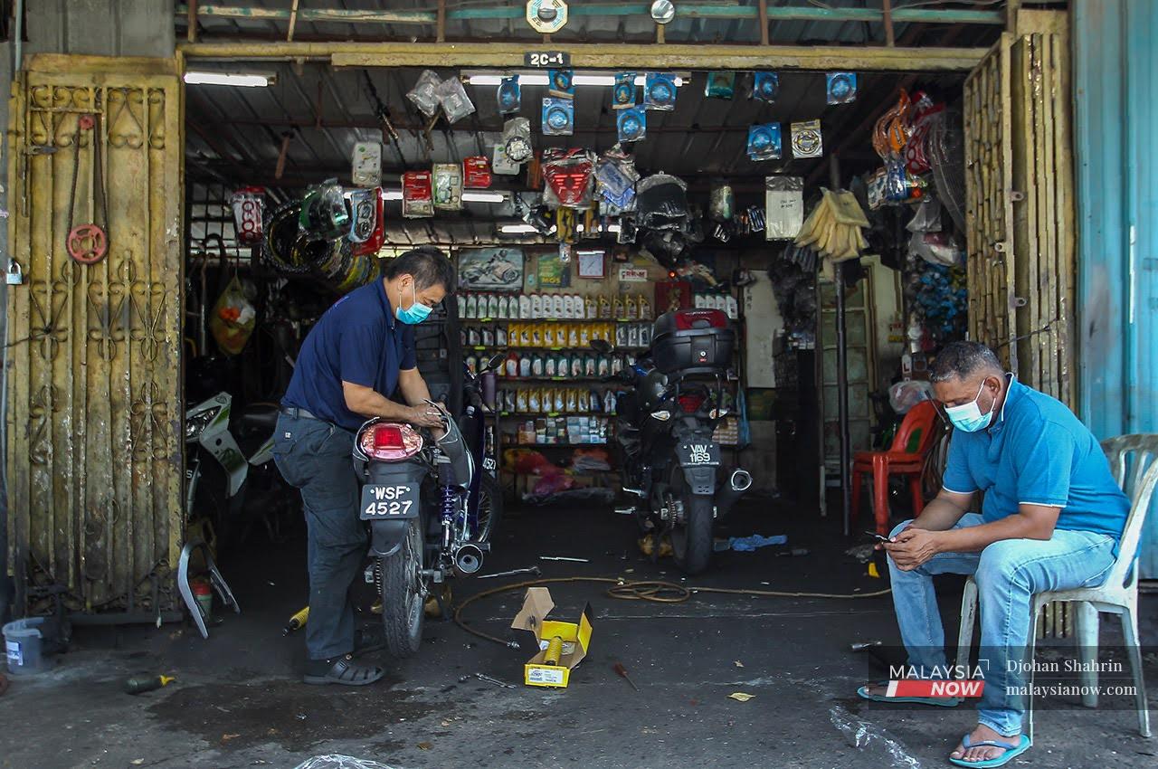 A mechanic repairs a motorcycle at his garage in Ampang.
