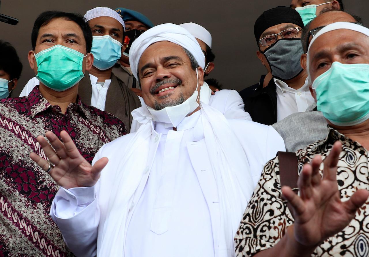 Indonesian Islamic cleric and leader of Islamic Defenders Front Rizieq Shihab (centre) gestures at reporters upon arrival at the regional police headquarters in Jakarta, Indonesia, Dec 12. Photo: AP