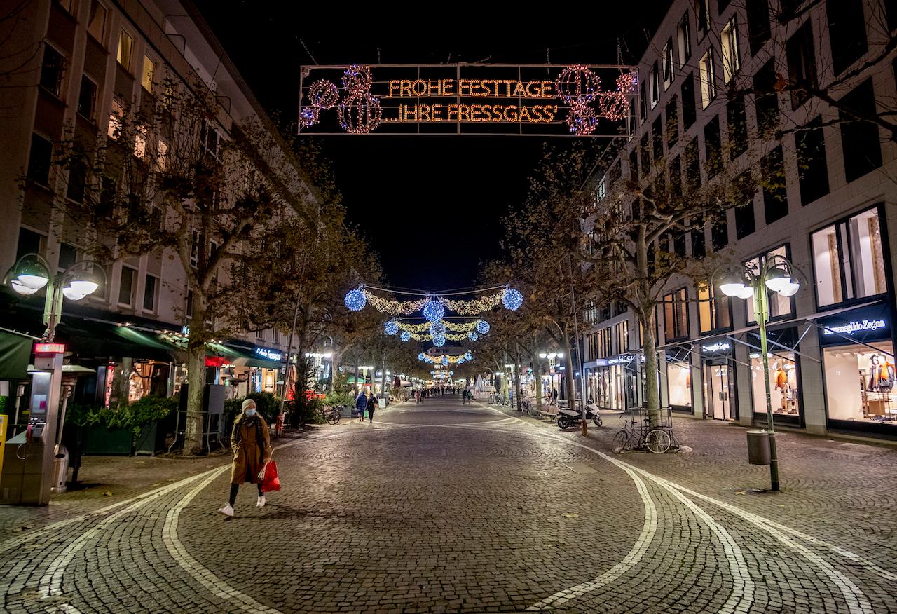 A woman with a face mask walks through an empty street in downtown Frankfurt, Germany, Dec 8. Photo: AP