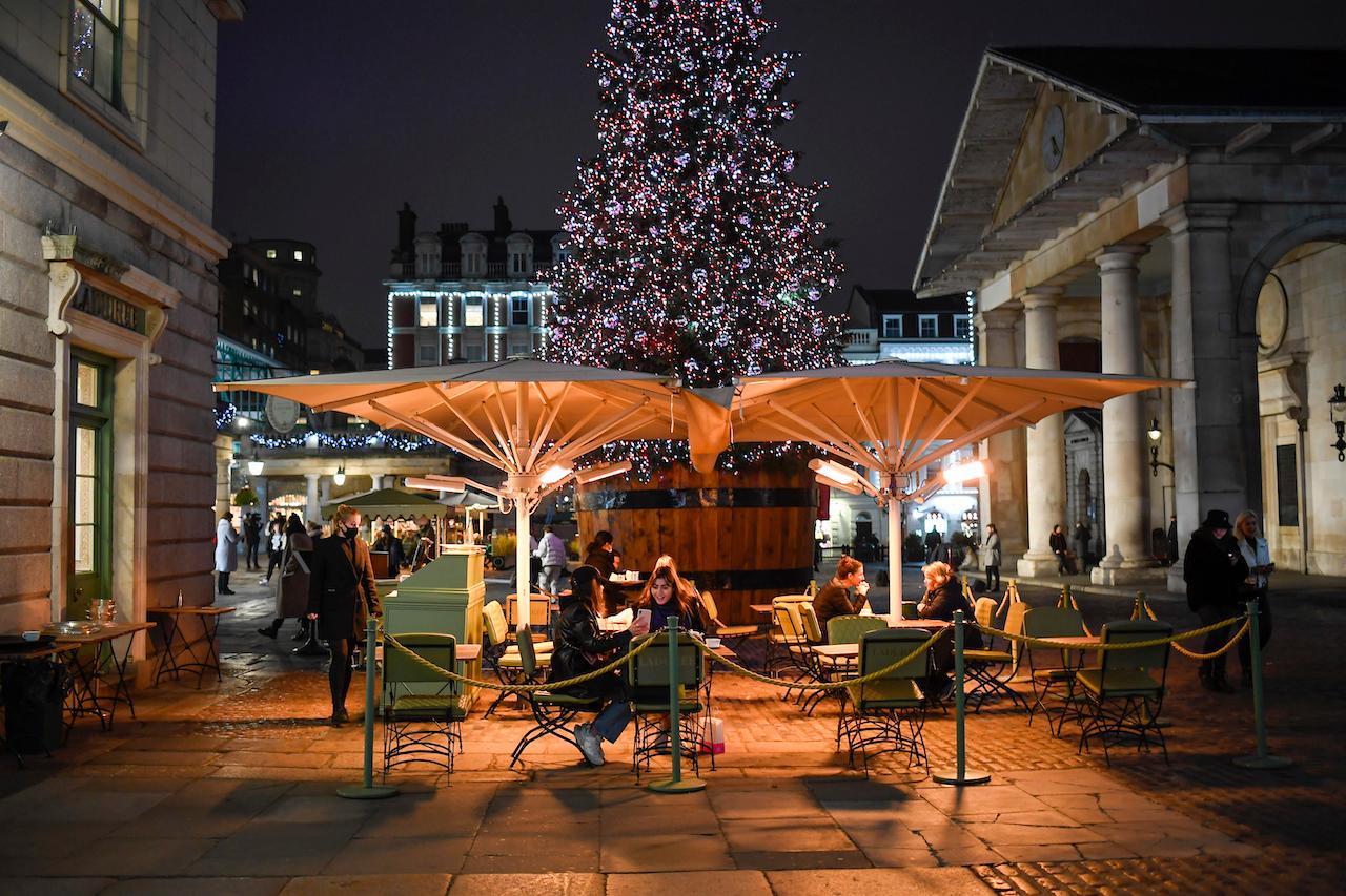 People eat outside in Covent Garden market, as non-essential shops are allowed to reopen after England's second lockdown ended in London, Dec 2. Photo: AP