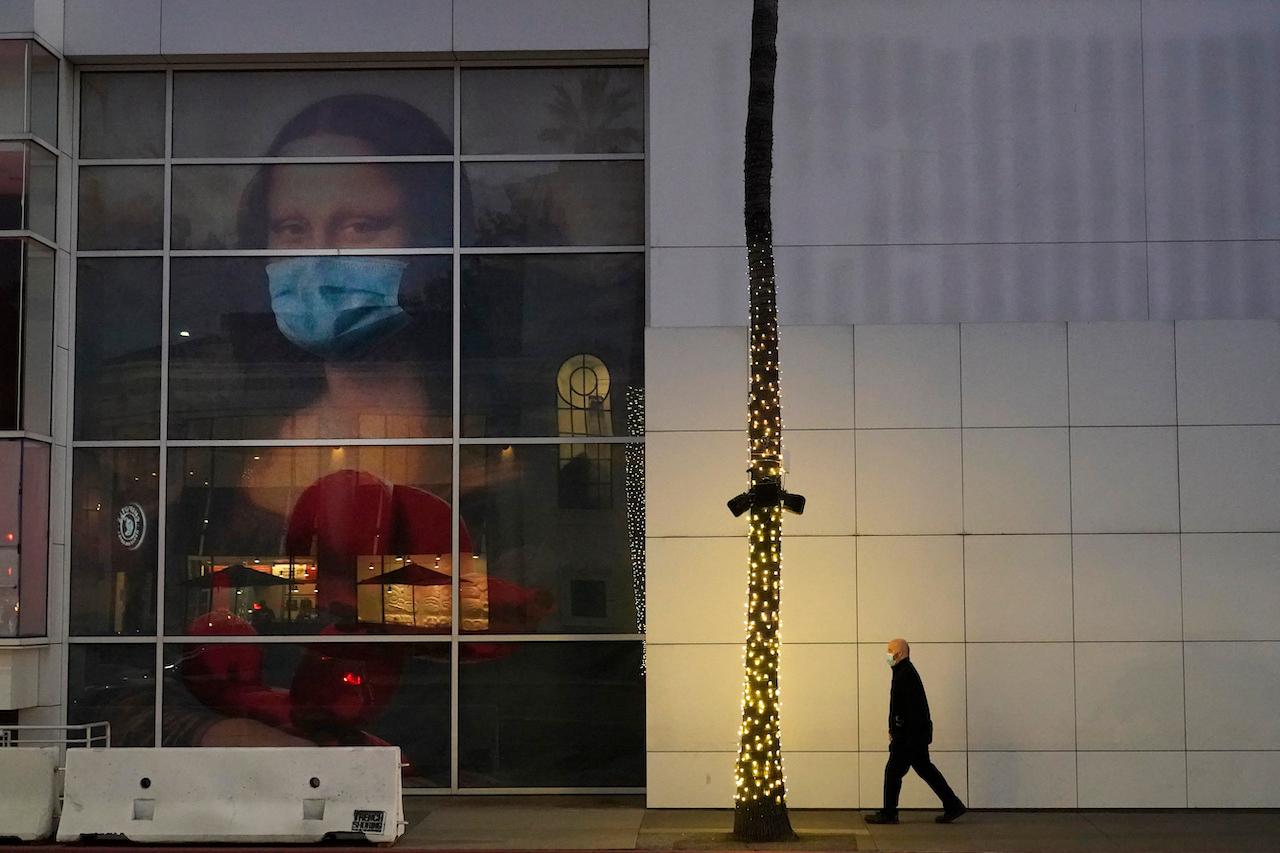A masked pedestrian walks past a Covid 19-themed mural depicting Leonardo da Vinci's Mona Lisa in Beverly Hills, California, Dec 9. Photo: AP
