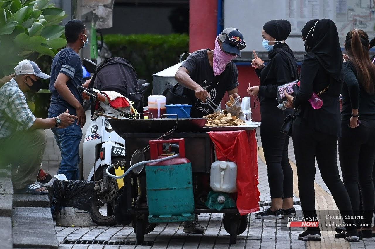 Seorang penjaja menjual makanan di Jalan Esfahan, Kuala Lumpur. SSM sedang merangka kaedah sesuai untuk membantu golongan terjejas seperti ibu tunggal.